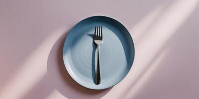 Top View of Blue Plate with Silver Fork on Pastel Pink Background in Minimal and Modern Style photo