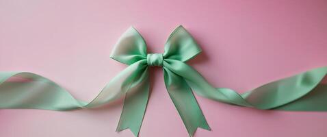 green ribbon tied in a bow on a pink background. photo