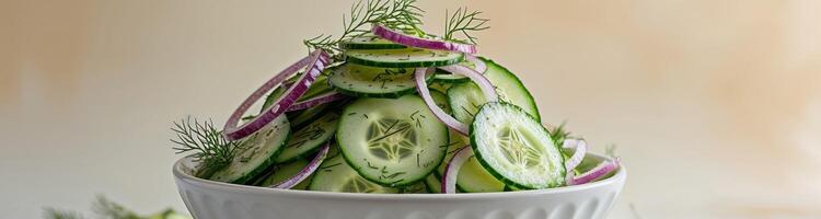 Fresh Thinly Sliced Cucumber Salad with Onions and Dill in a White Bowl on a Light Background photo