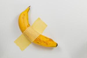 Banana taped with transparent adhesive on white background photo