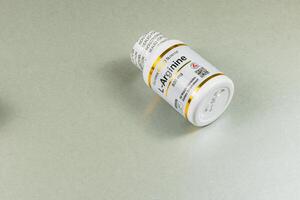 Lviv Ukraine 10.04.25 Bottle of L Arginine supplement on a gray surface photo