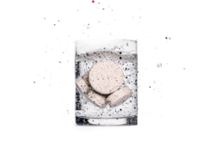 Effervescent tablets dissolving in a glass of water with splashing effect png