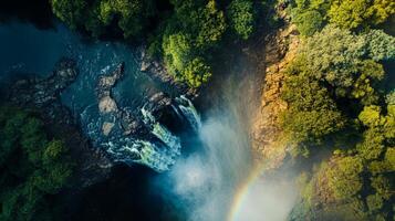 Aerial view of lush waterfall and vibrant rainbow in dense forest landscape photo