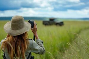 Female photographer capturing wildlife in vast grassland with cloudy skies photo