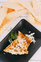 close-up of a delectable grilled sandwich decorated with shredded cheese and fresh herbs, set against a decorative background, emphasizing a pleasant and inviting culinary presentation. photo