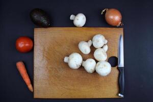 Cooking a vegetable dish. There are mushrooms on the board and fresh vegetables nearby photo