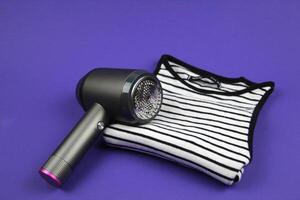 On a purple background lies a T-shirt, and on it is a machine for removing pellets. Concept of clothing care. photo