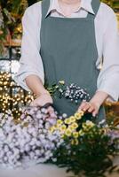 florist works preparing beautiful floral arrangement. Various flowers and materials lie on table, emphasizing the artistic and inspiring atmosphere associated with floral design and presentation photo