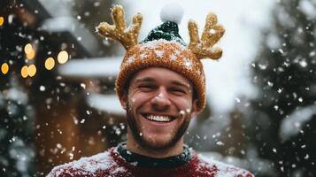 A man wearing a reindeer hat in the snow photo