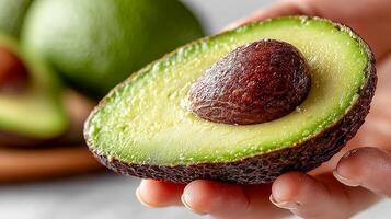 A close-up of an avocado with the pit inside lying in a person's hand photo