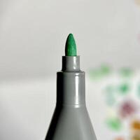 Close up green marker stationary felt nib isolated on square paper surface background. photo