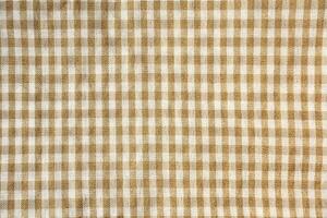 Square checkered brown and white colored picnic table cloth texture isolated on horizontal background from top angle view. photo