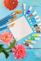summer background. paints, brushes and a canvas on a blue wooden background. art. space for a text photo