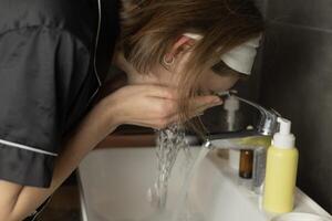A woman washes her face in the bathroom photo