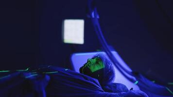 Patient lies on linear accelerator for radiotherapy, while medical professional operates the equipment using a control device. The advanced machine and modern clinic setting ensure precise treatment video