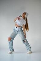 Young beautiful hip-hop dancer posing on a studio gray background photo