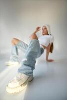 Young woman sitting on the floor in front of white wall and looking at camera photo