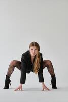 modern style dancer posing on studio background, wearing black jacket and high heels photo