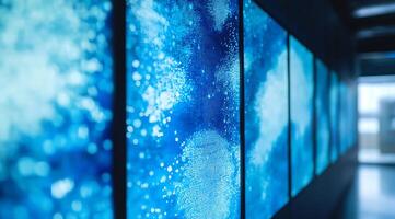 A row of large digital displays showcasing abstract blue and white patterns in a modern minimalist setting. photo
