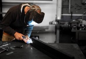 A man in a welding helmet working on a piece of metal photo
