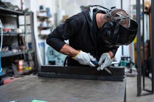 A man in a welding helmet working on a table photo