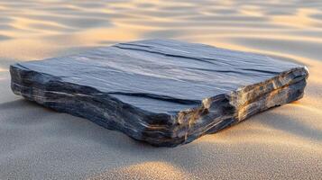 A flat, textured rock on sandy terrain. photo