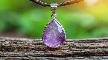 A purple gemstone pendant hanging on a wooden branch. photo