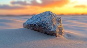 A rock on sandy terrain during sunset. photo