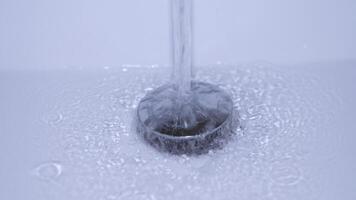 A stunning closeup shot of refreshing water dynamically flowing into a drain, showcasing splashes and tiny bubbles video