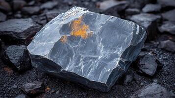 Dark rock with orange streak on a textured surface. photo