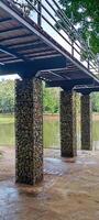 Bridge Columns by the Lake. A pedestrian bridge stands firmly supported by gabion columns over a tranquil lakeside path. photo