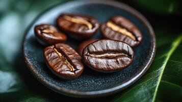 Coffee beans on a plate with green leaves. on dark plate photo