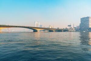 Vibrant view of a bridge crossing a river in a bustling city during a sunny day photo
