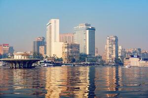 City skyline reflection on the Nile River with modern buildings in Cairo during a clear day photo