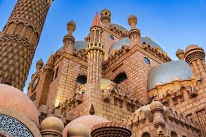 Majestic architecture of an ancient mosque with intricate design and towering minarets against a bright blue sky photo
