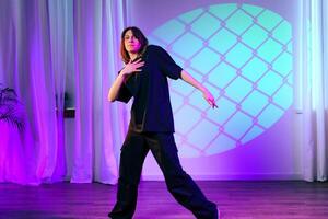 Female dancer performs expressive routine under colorful lights in studio setting photo