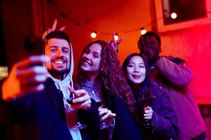 Friends enjoying a night out at a party with drinks and vibrant lights in an urban setting photo