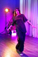 Professional dancer performs in stylish outfit during a vibrant indoor dance session in colorful lighting photo