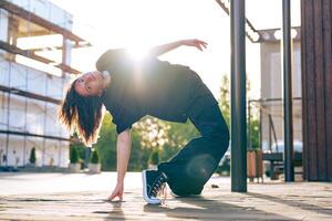 Dancer performs a unique move in urban setting during sunset in the city photo