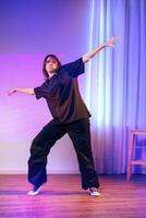 Dance performance featuring a person in casual black attire against a colorful backdrop in a studio setting photo