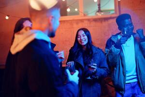 Friends enjoy an evening gathering with drinks while celebrating under string lights in an outdoor setting photo