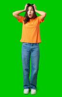 Surprised woman expressing shock while standing on a bright green background in a casual outfit photo