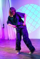Dancer performing an expressive routine in a contemporary studio space with colorful lighting and shadows photo