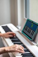 Hands playing a keyboard while following an interactive learning app on a tablet. Technology enables self-education in music without traditional lessons. High quality photo