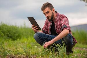 Farmer Plantation checking quality by tablet agriculture modern technology Concept. Smart farming, using modern technologies in agriculture. Man agronomist farmer with digital tablet computer. photo