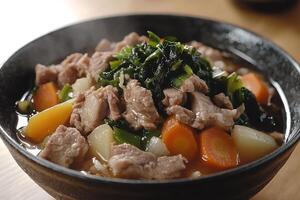 A bowl of meat and vegetables with broth photo
