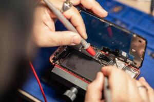 Expert performs smartphone battery repair with precision tools at a tech workshop photo
