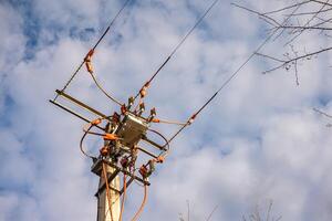 electrical pole with transformer and wires power line equipment against cloudy sky photo