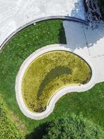 Top-down aerial shot of a small, geometric pool with murky water from poor upkeep. photo