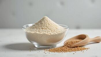 Flour and Mustard Seeds Arranged in a Clear Bowl With a Wooden Scoop on a Neutral Background photo